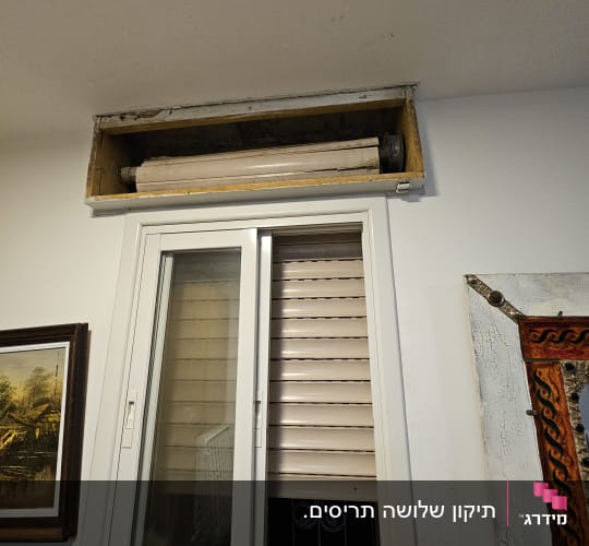 תריס גלילה פתוח למחצה מעל חלון זכוכית